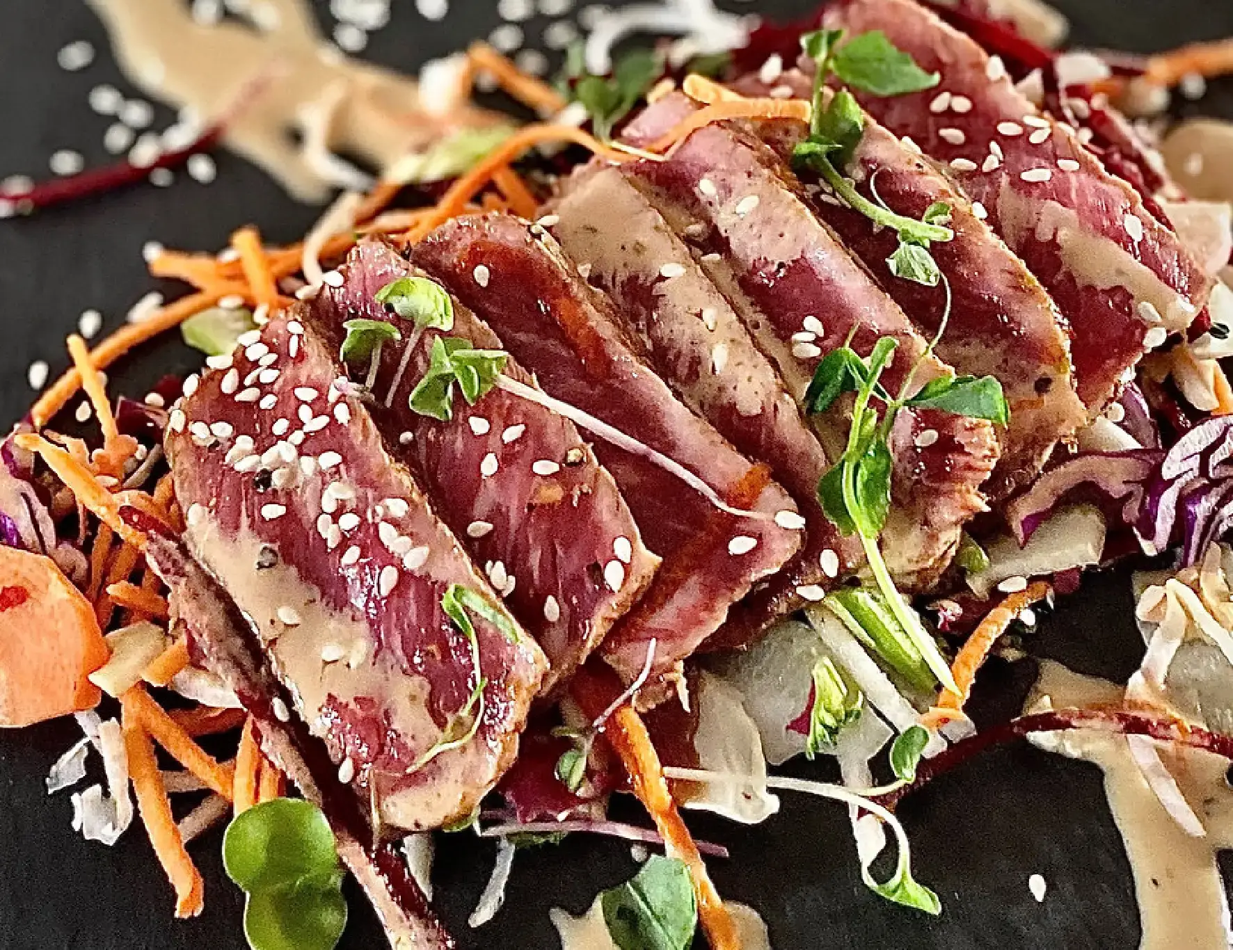 Bœuf saisi tranché, parsemé de sésame, sur un lit de crudités