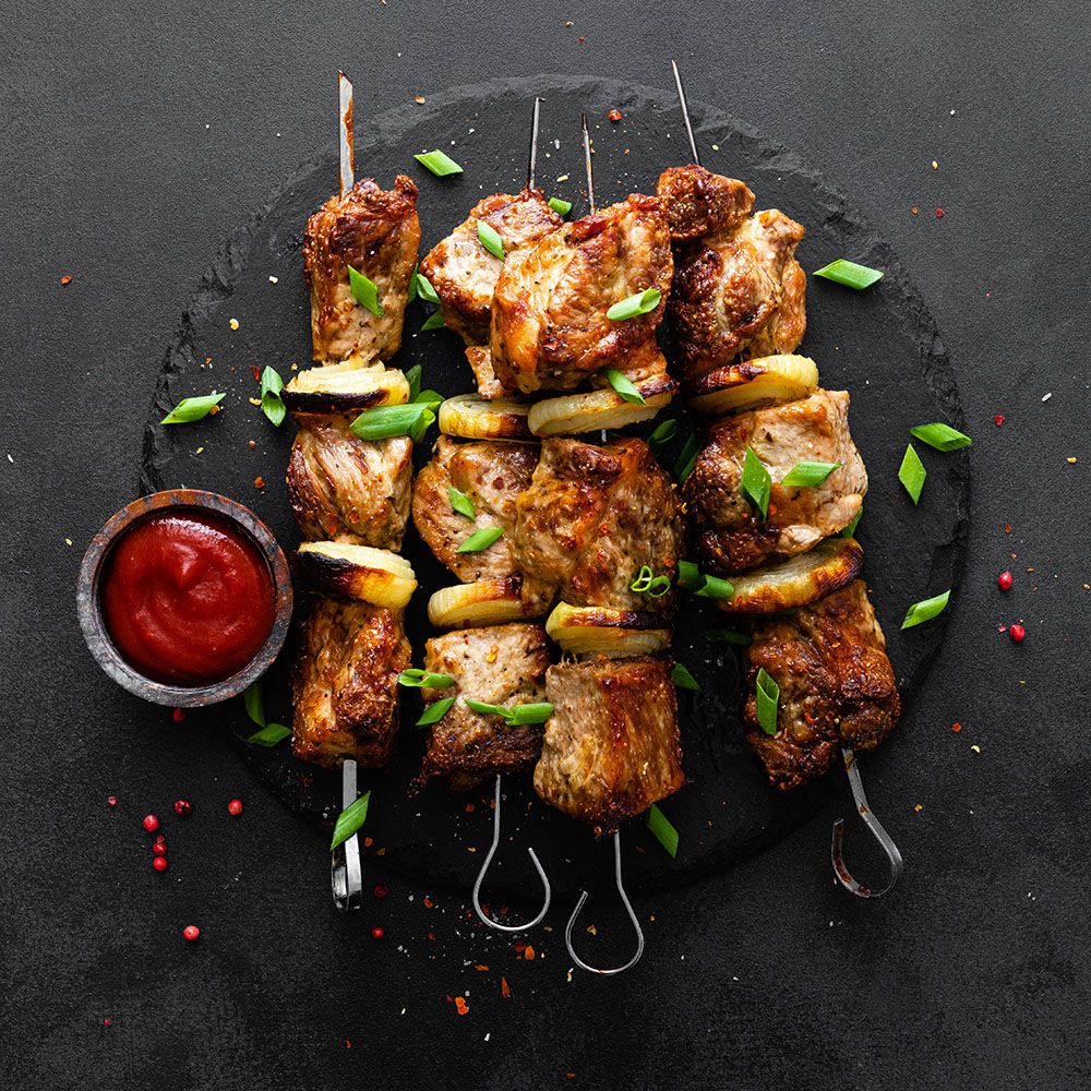 Brochettes de viande grillées, oignons et ciboule, servies sur une ardoise