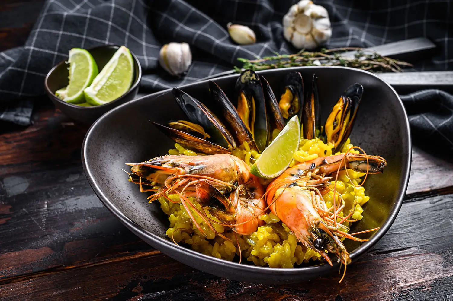 Paëlla aux crevettes, moules et citron, servie dans une assiette creuse
