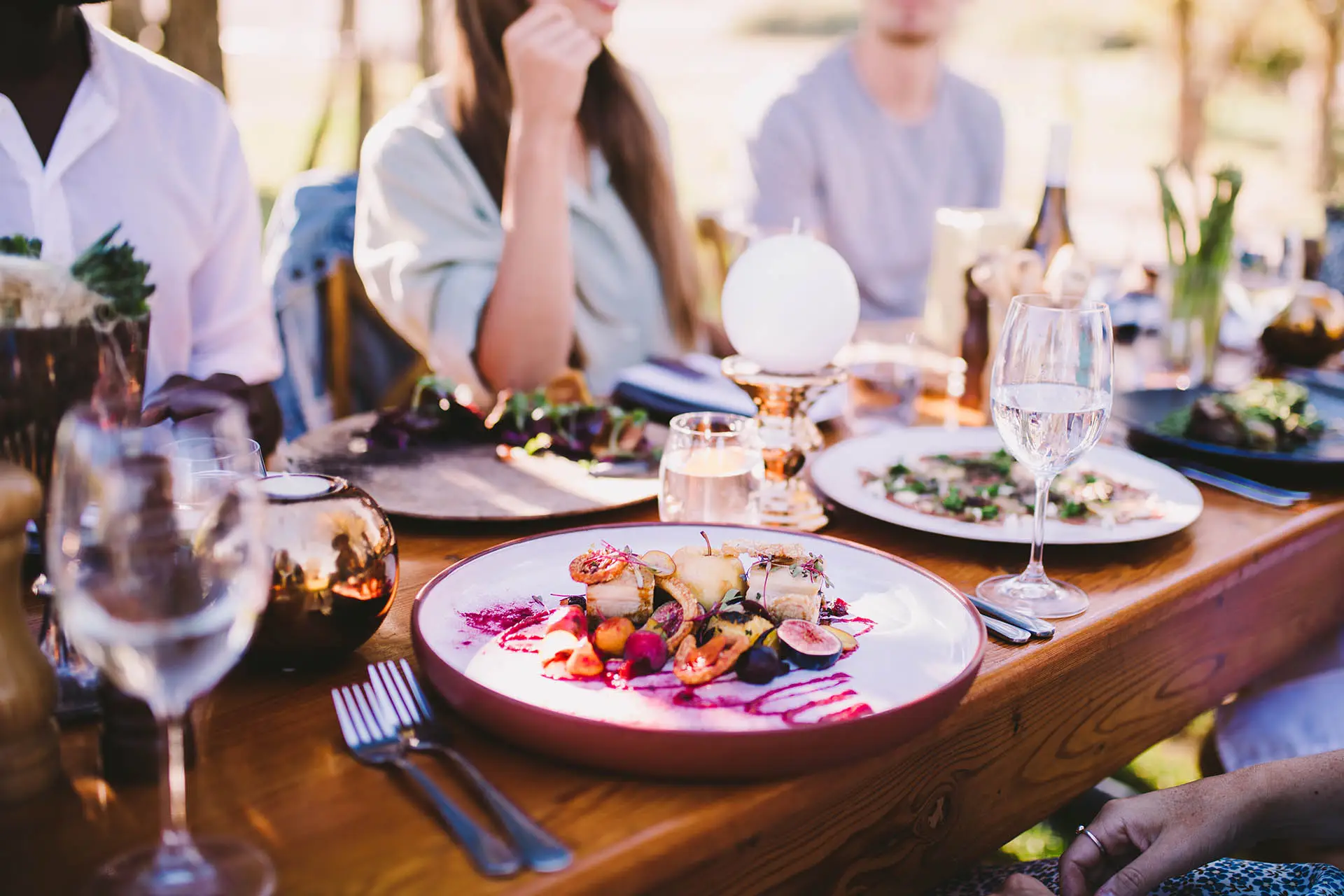 Plats partagés sur une grande table en extérieur, entourée de convives